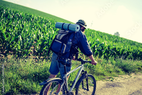 hipster man on a bicycle in the countryside