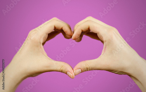 Heart shape made of two beautiful palms. isolated on purple.
