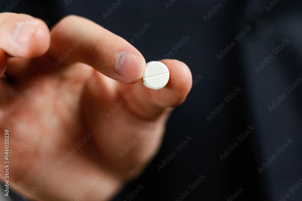 Businessman holds one round tablet with two fingers Businessman holds one round tablet with two fingers