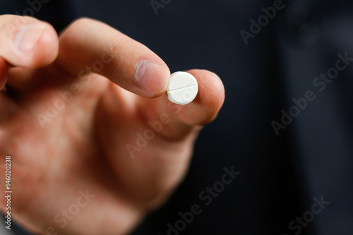 Businessman holds one round tablet with two fingers