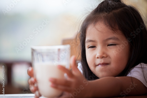 Closeup child hand holding a glass of milk in vintage color tone