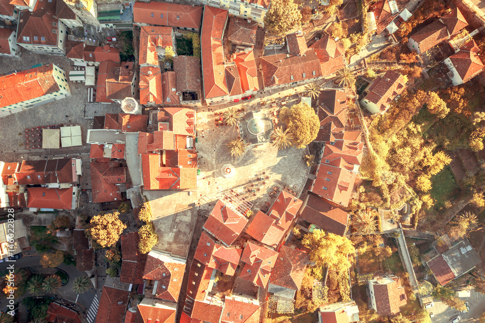 Top view of the city streets with red roofs of houses and highways in the sunlight