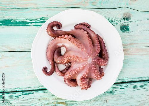 Octopus on white plate and wooden background.
