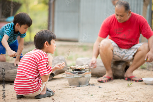 Asain Father and son making barbecue togheter outdoor activity