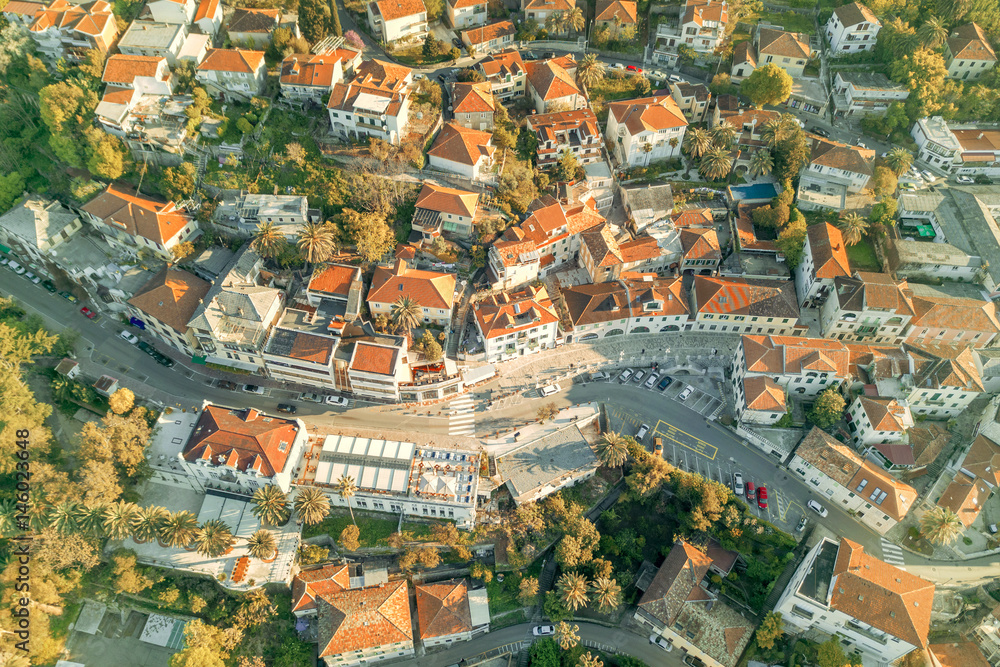 Top view of the city streets with red roofs of houses and highways in the sunlight