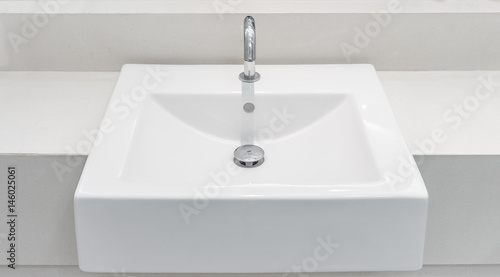 White ceramic wash basin with a automatic tap and drain. It is also known as sink, sinker, washbowl and hand basin.
