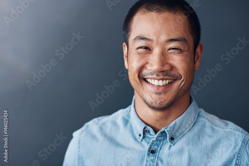 Smiling young Asian designer standing in an office