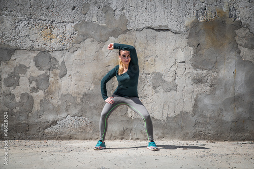 fitness girl in sport clothes on wall background