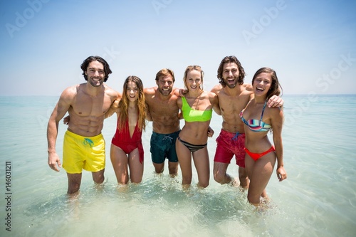 Cheerful couples in beachwear standing in sea