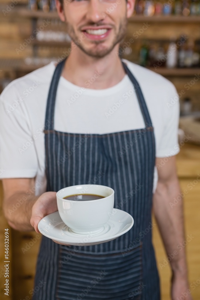Smiling waiter offering cup of coffee Smiling waiter offering cup of coffee
