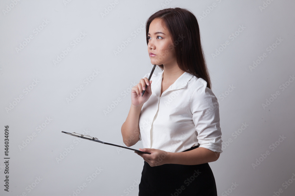 Young Asian business woman thinking with pen and clipboard.