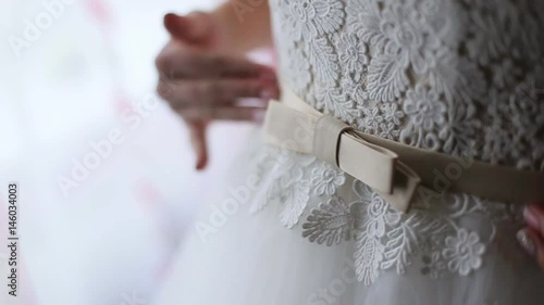 Bride preparing for wedding ceremony. Close up beautiful white wedding dress with bow.