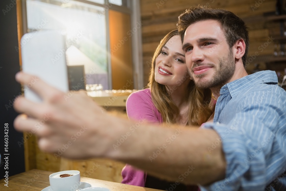 Young couple taking selfie on mobile phone while having coffee