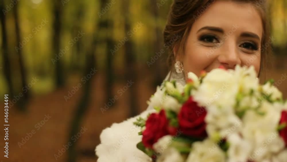 Portrait of beautiful bride smiling looking at the camera in the autmn park in slow motion. Close up Portrait of beautiful bride smiling looking at the camera in the autmn park in slow motion. Close up