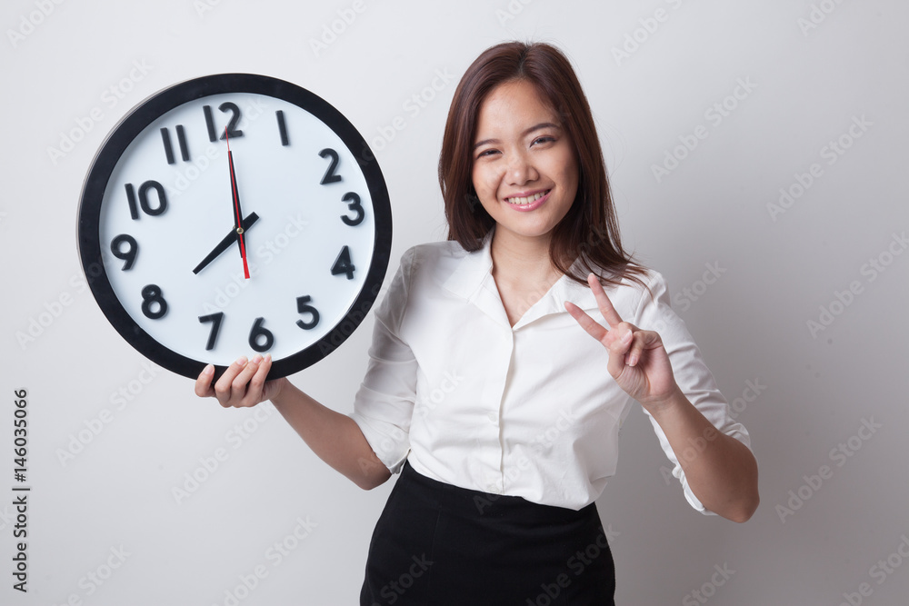 Young Asian business woman show victory sign with a clock. Young Asian business woman show victory sign with a clock.