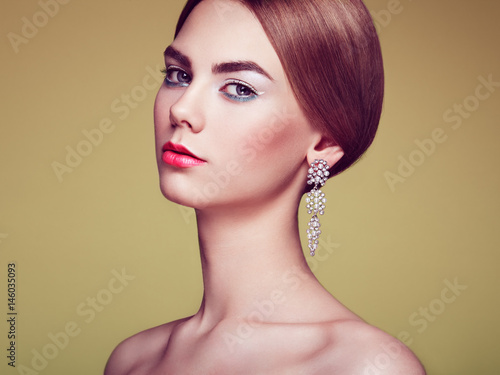 Fashion portrait of young beautiful woman with jewelry. Blonde girl. Perfect make-up and hairstyle. Beauty style woman with diamond accessories. Silver earrings