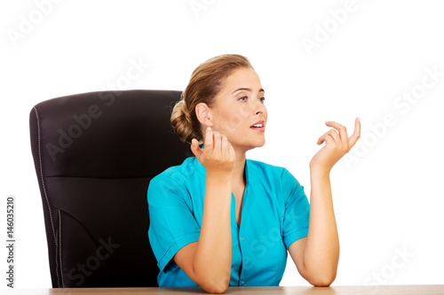 Εκτύπωση καμβά Female doctor sitting behind the desk and talking with someone