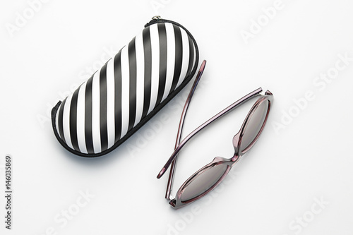 Black and white striped case and sunglasses isolated on white background