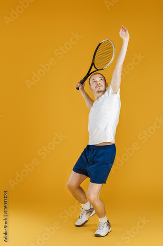 young tennis player plays tennis on yellow background © producer