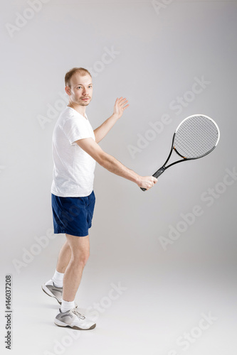 young tennis player plays tennis on grey background