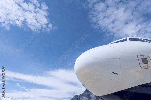 Flugzeugnase vor blauem Himmel mit Wolken