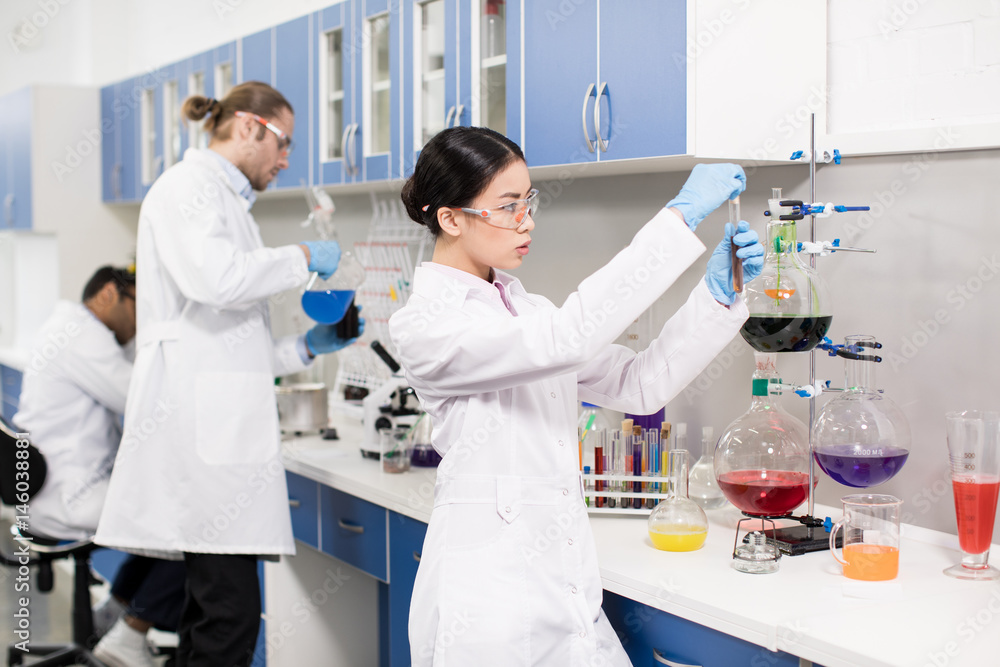 Group of young professional scientists making experiment in research laboratory Group of young professional scientists making experiment in research laboratory