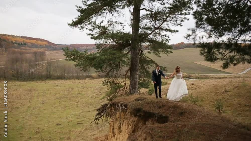 Bride and groom walking on the hill of the mountain. Mountain top Bride and groom walking on the hill of the mountain. Mountain top