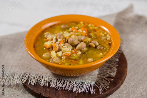 Mushroom potato and carrots soup in a clay plate on a gray napkin