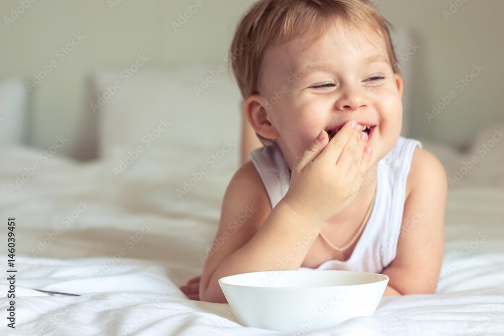 Little cute boy having breakfast in bed. Boy playing in bed. Breakfast in bed. Little cute boy having breakfast in bed. Boy playing in bed. Breakfast in bed.