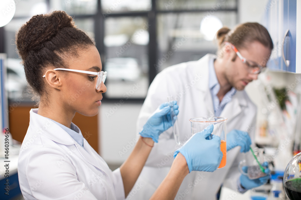 side view of concentrated scientists working in laboratory side view of concentrated scientists working in laboratory