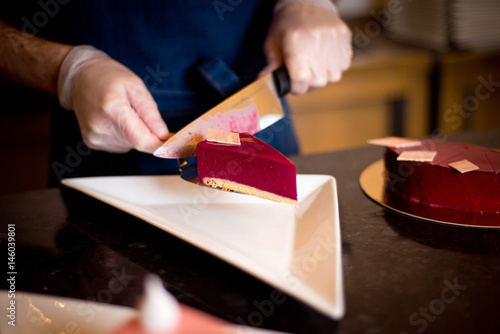 waiter or chef cuts the cake and spread on a plate