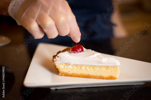 waiter or chef cuts the cake and spread on a plate photo