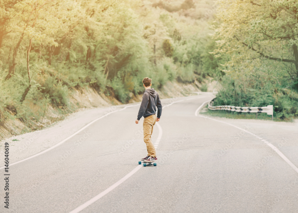 Fototapeta premium Man riding a longboard on mountain road