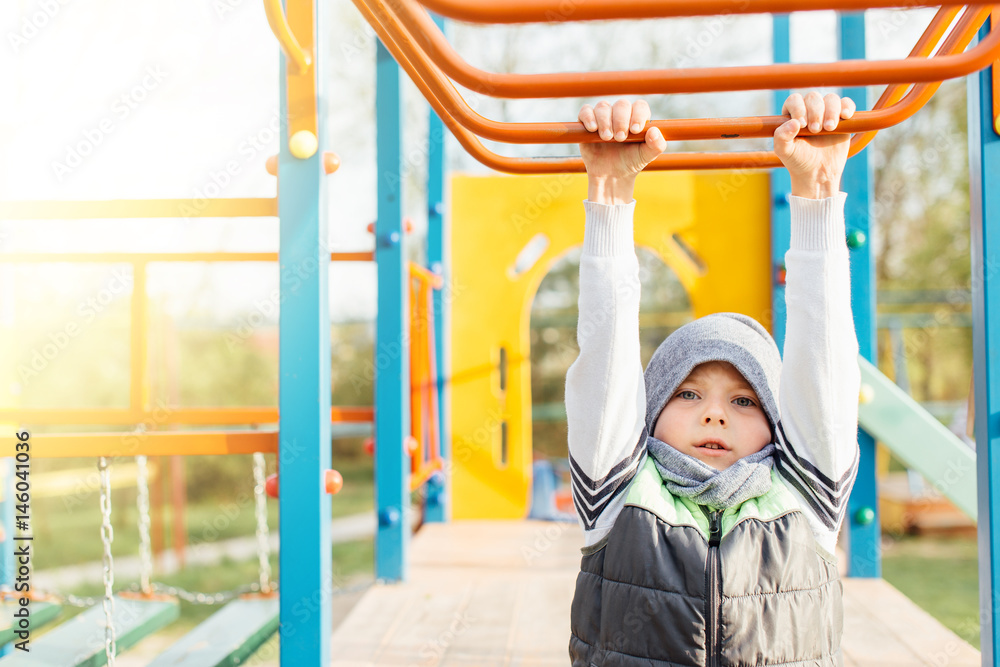 Fototapeta premium Little boy play on playground with blur park background