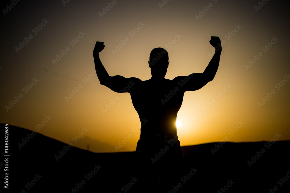 muscular man silhouette at sunset sky