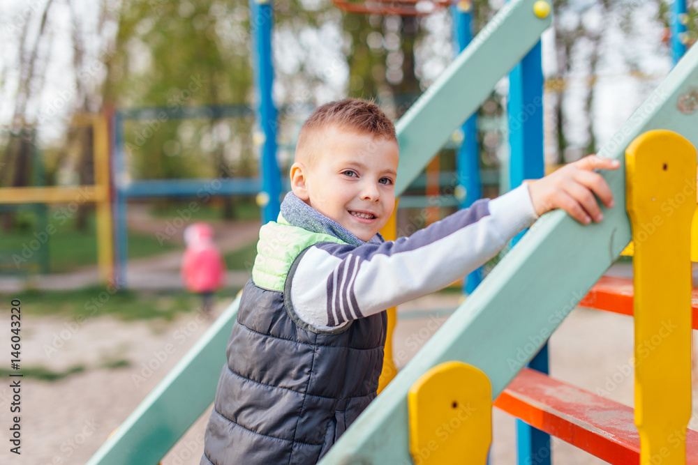 Little boy play on playground with blur park background Little boy play on playground with blur park background