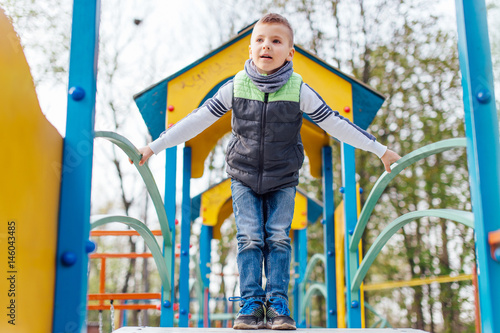 Fototapeta Naklejka Na Ścianę i Meble -  Little boy play on playground with blur park background