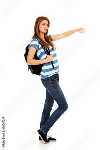 Teenager woman with backpack pointing for soomething