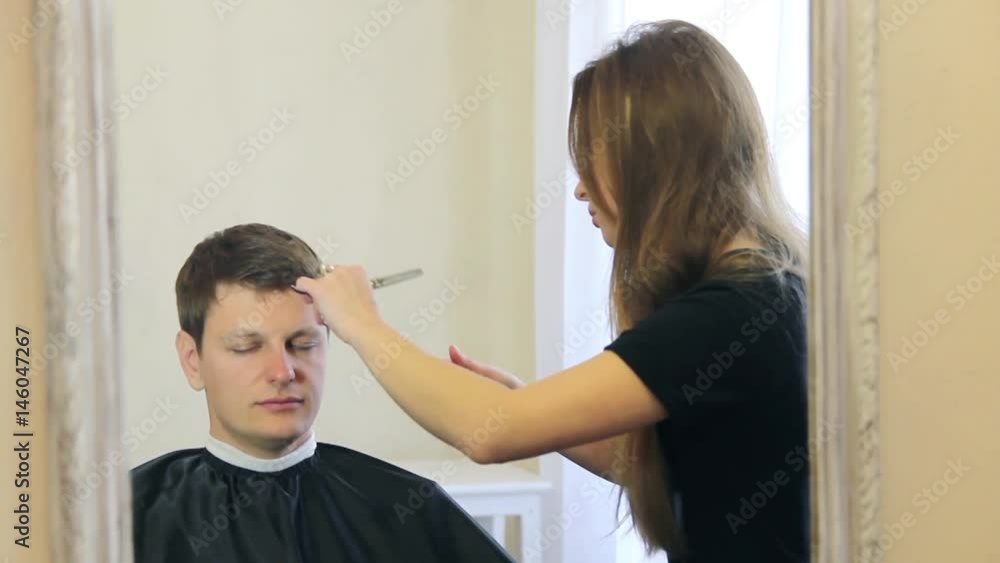 Woman getting a haircut by a professional hairdresser using comb and grooming scissors Woman getting a haircut by a professional hairdresser using comb and grooming scissors