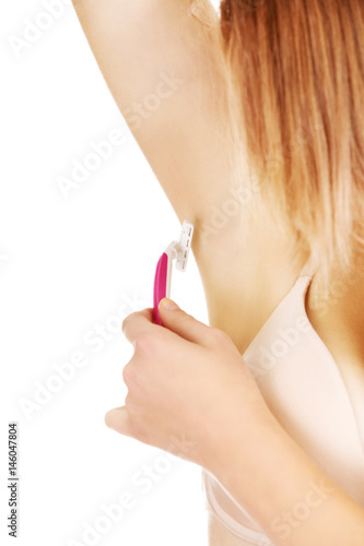 Young woman shaving armpit pink razor