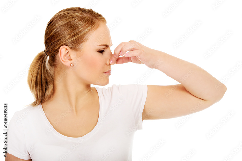 Young woman holding her nose because of a bad smell Young woman holding her nose because of a bad smell