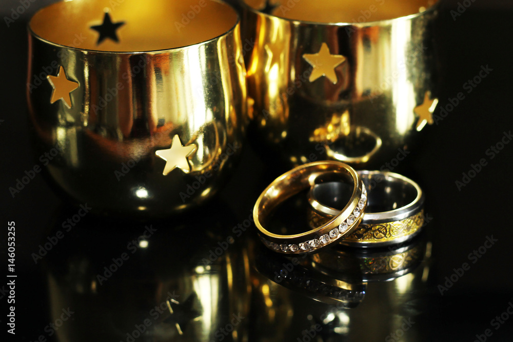 Candlestick and wedding rings on a black background