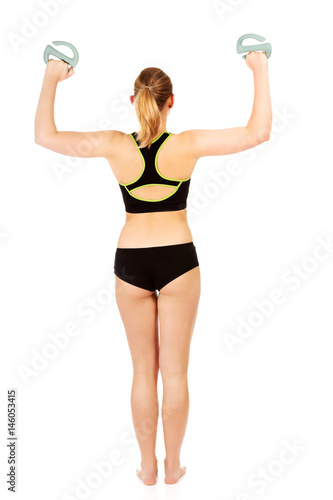 Back view of fitness woman exercising with weigh 