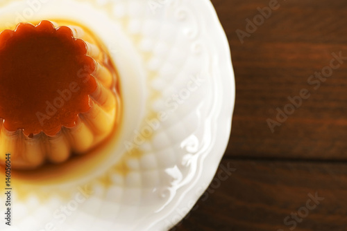 From above white plate with flan on the wooden background. Horizontal shoot ..