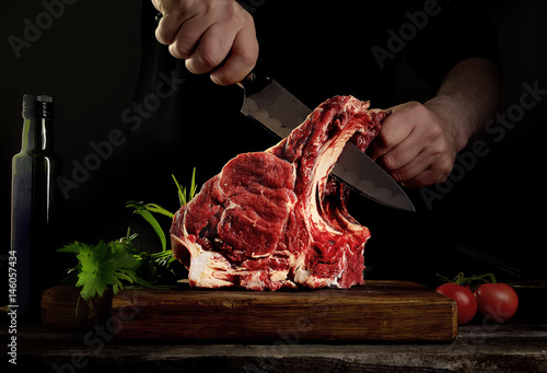 Man cutting raw beef meat.
