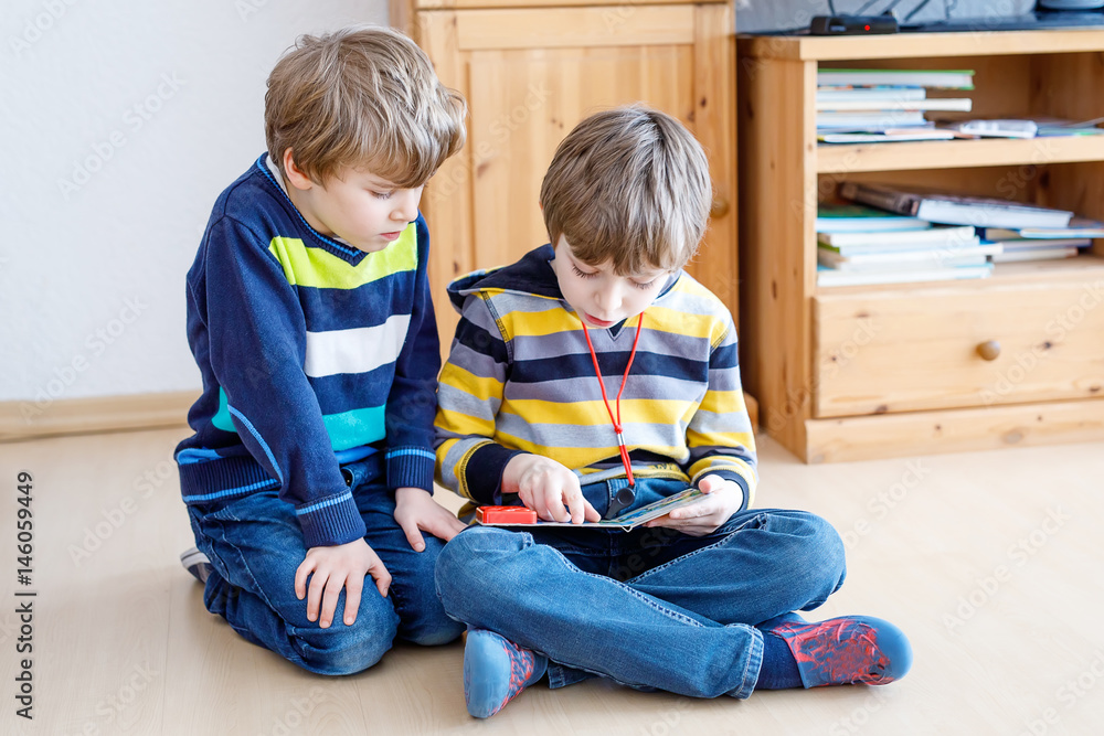 Two little kid boys reading a book at home Two little kid boys reading a book at home