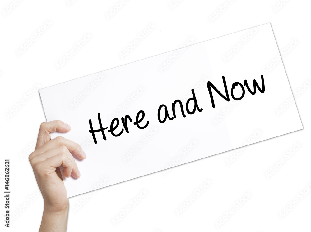Here and Now Sign on white paper. Man Hand Holding Paper with text. Isolated on white background Here and Now Sign on white paper. Man Hand Holding Paper with text. Isolated on white background