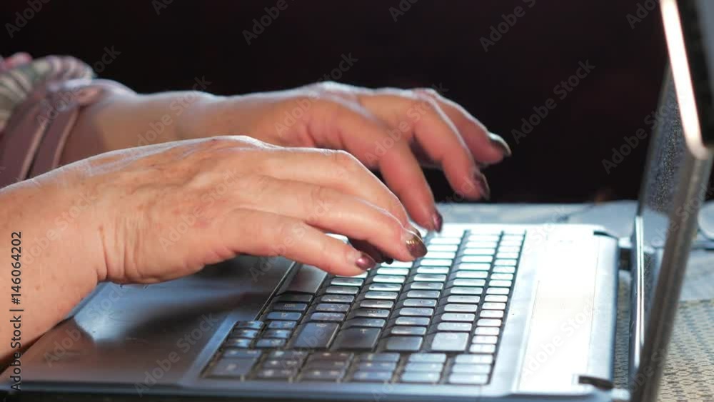 An older woman checks the messages on social networks on a laptop at home. She sits at the table An older woman checks the messages on social networks on a laptop at home. She sits at the table