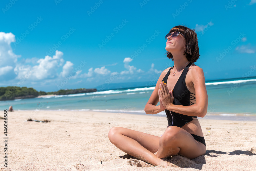 Young healthy attractive woman practicing yoga on the beach Nusa Dua, tropical Bali island, Indonesia.