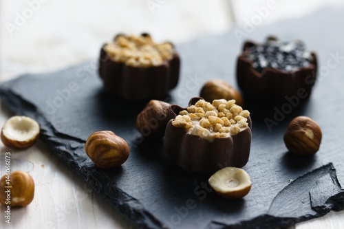 Chocolate cup pralines on slate stone serving board with hazelnuts decoration
